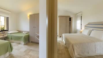 A hotel room with two single beds, a wardrobe, a bedside table with a lamp, and a view of the outdoors.