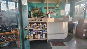 A bookstore with a teal interior, a reception desk, and a variety of books and magazines on display. - Tiki Village (Vernon)