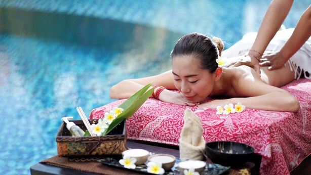 A person receiving a massage by a poolside with a tray of amenities. - Best Western Resort Kuta (Kuta)