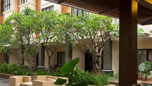 A courtyard with outdoor seating, potted plants, and a water feature. - Best Western Resort Kuta (Kuta)