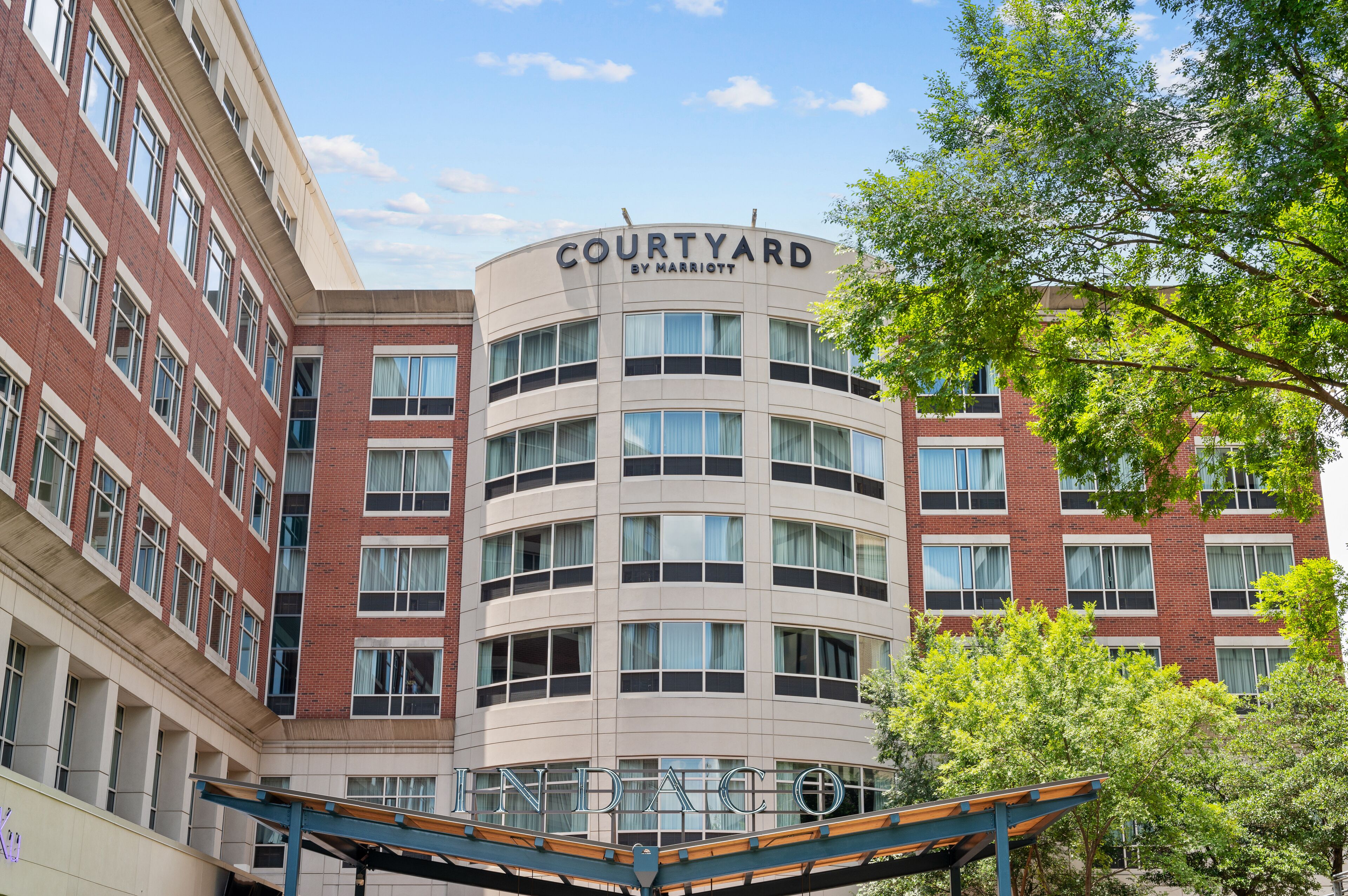 A multi-story hotel with a curved facade, featuring a prominent sign that reads "COURTYARD BY MARRIOTT."