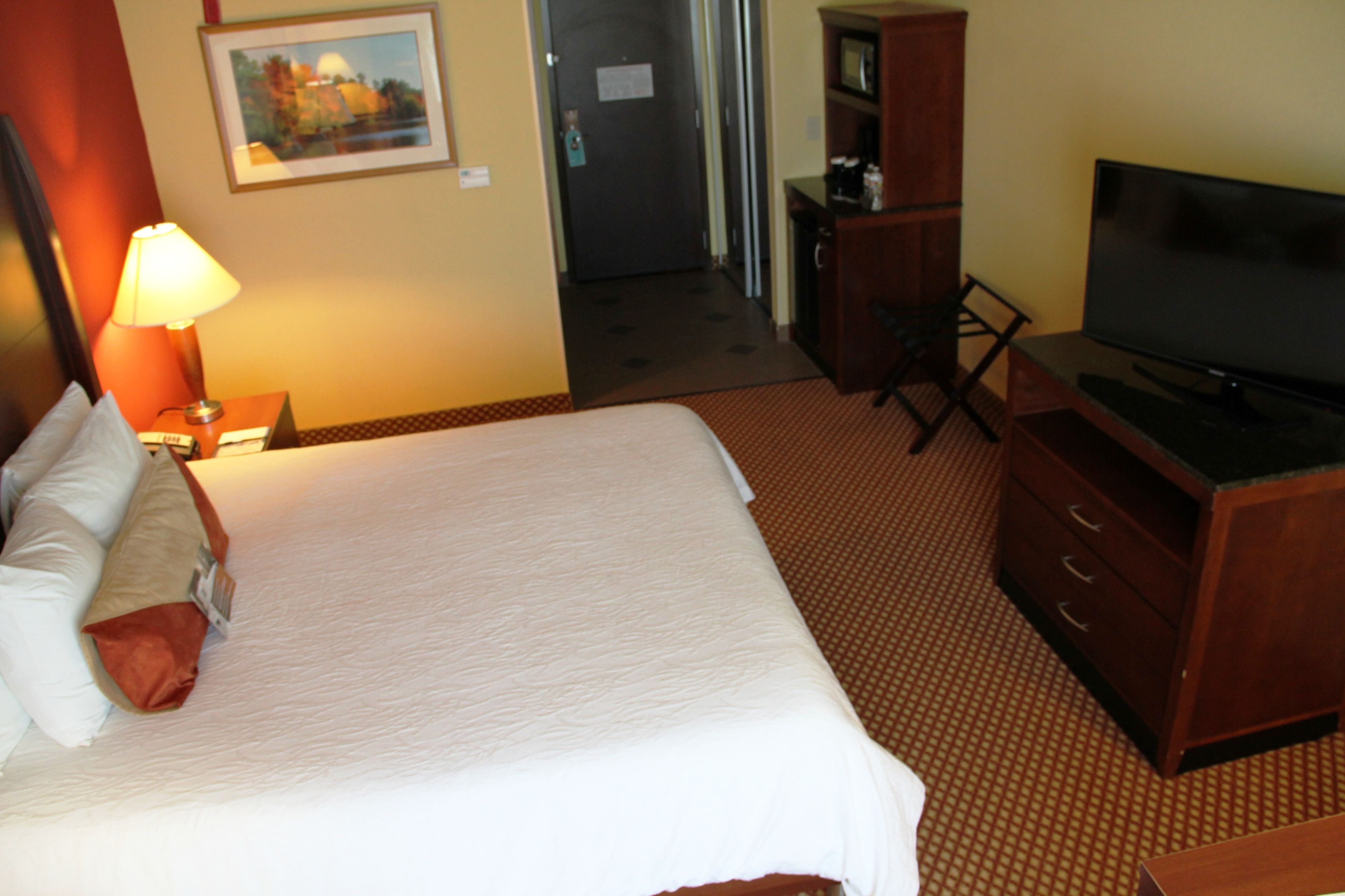 Ein Hotelzimmer mit Bett, Fernseher, Schreibtisch und Lampe.