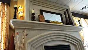 Une cheminée surmontée d’un miroir, une bougie et des appliques murales.
