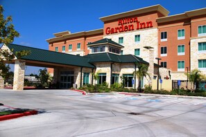 A Hilton Garden Inn with a stone facade, green roof, and multiple windows. - Hilton Garden Inn Houston West Katy (Katy)