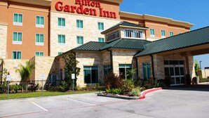Un hôtel Hilton Garden Inn doté d’une façade en pierre, de nombreuses fenêtres et d’un toit végétalisé.