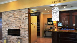Une cuisine avec un mur en pierre, une enseigne indiquant « The Pantry », et un comptoir avec une machine à café.