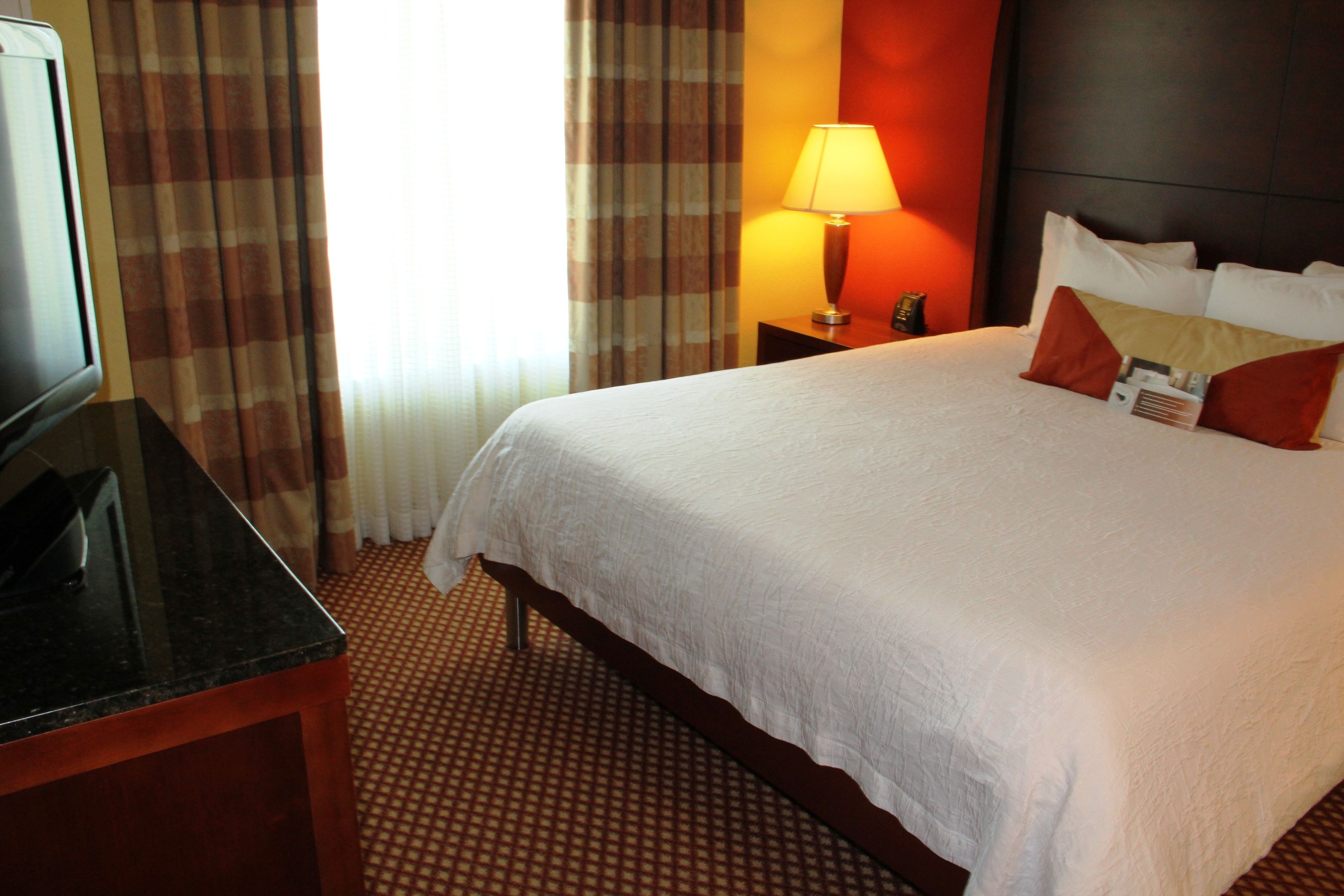 A hotel room with a bed, a TV, a lamp, and a nightstand.