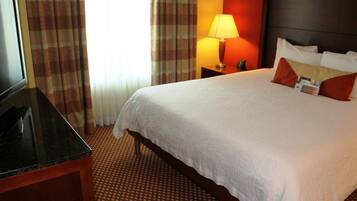 A hotel room with a bed, a TV, a lamp, and a nightstand.