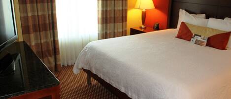 A hotel room with a bed, a TV, a lamp, and a nightstand.