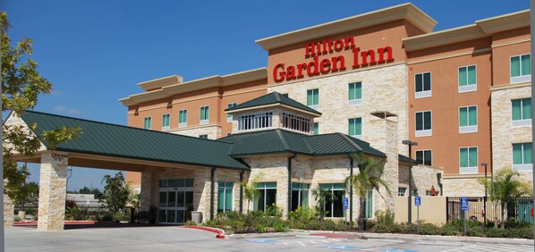 A Hilton Garden Inn with a stone facade, green roof, and a clear blue sky. - Hilton Garden Inn Houston West Katy (Katy)