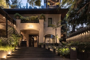 A modern hotel entrance with a staircase leading to the lobby, surrounded by lush greenery and well-lit pathways. - Brick Hotel - Small Luxury Hotels of the World (Mexico City)