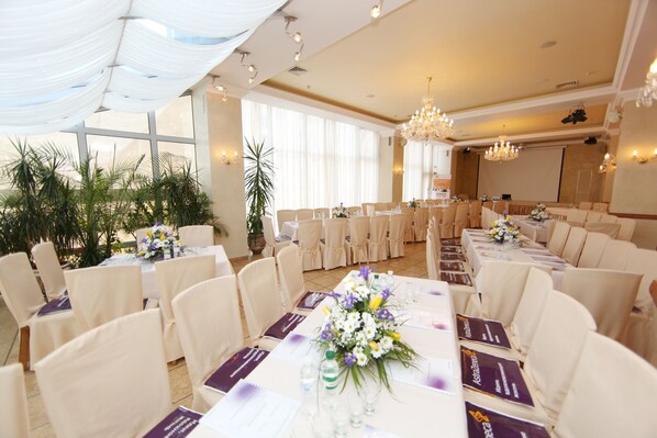 Un salón de banquetes con filas de mesas, sillas y una pantalla grande.