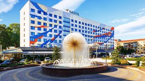 A hotel with a modern facade, a central fountain, and a clear blue sky. - Nadiya Hotel (Ivano-Frankivsk)