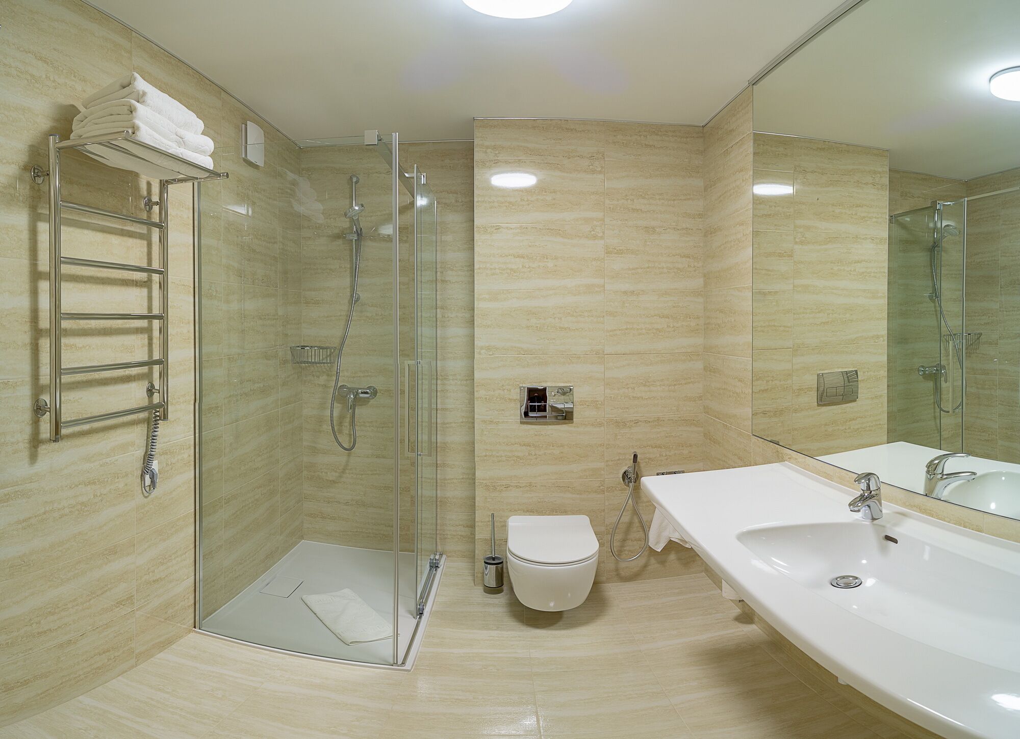 A modern bathroom with a glass-enclosed shower, a white toilet, and a large vanity with a mirror.