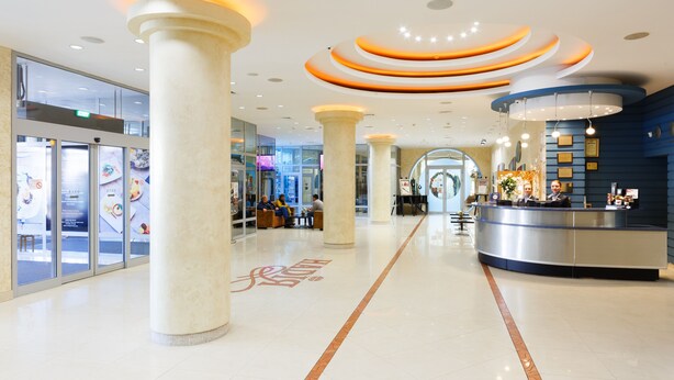 A spacious lobby with a central reception desk, large pillars, and a modern ceiling design. - Nadiya Hotel (Ivano-Frankivsk)