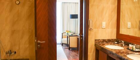 Une salle de bain d’hôtel avec une baignoire, deux lavabos et un grand miroir.