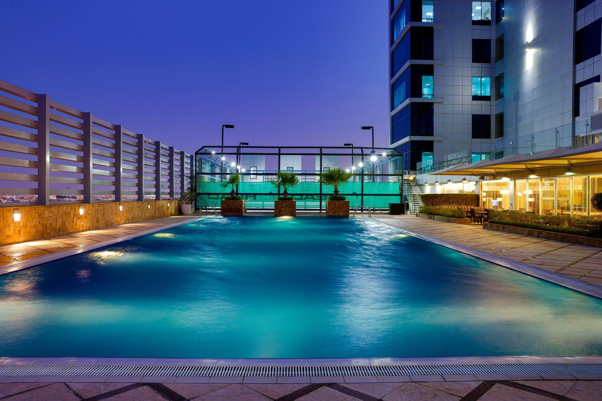 Piscina com vista para a paisagem urbana ao anoitecer.