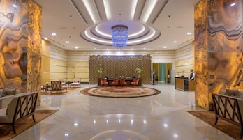 A spacious lobby with a reception desk, seating area, and a chandelier.