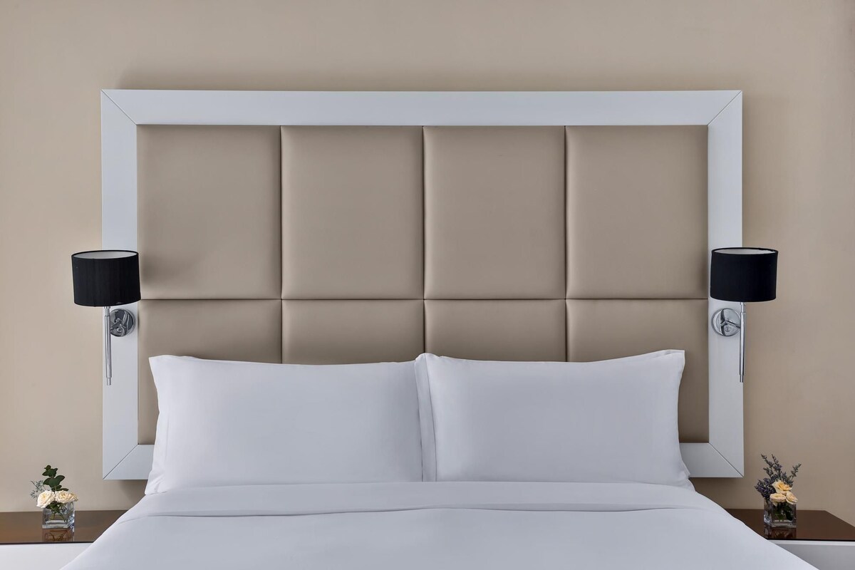 A bed with a white headboard and two bedside lamps.