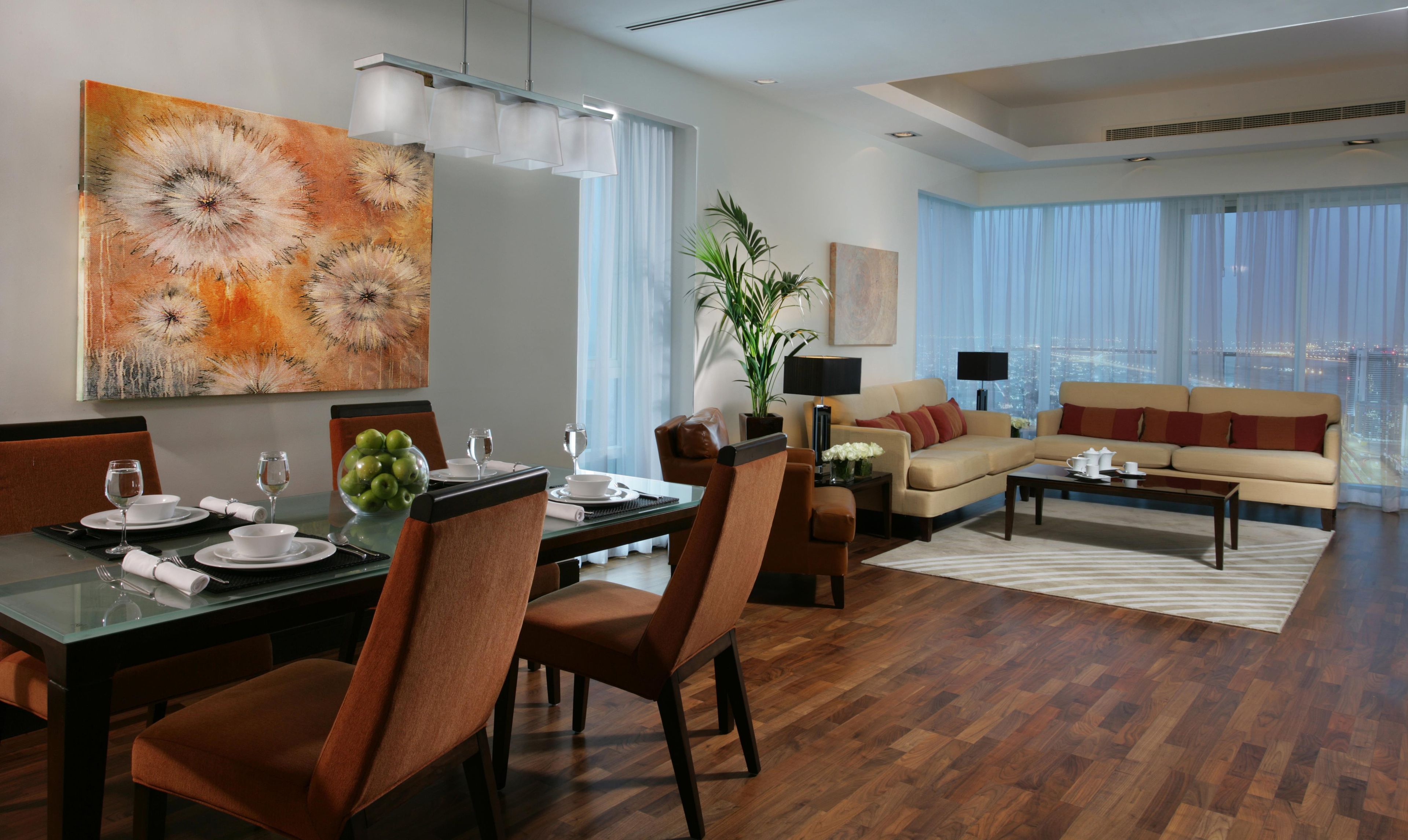 A modern living room with a dining area, featuring a city view through large windows.