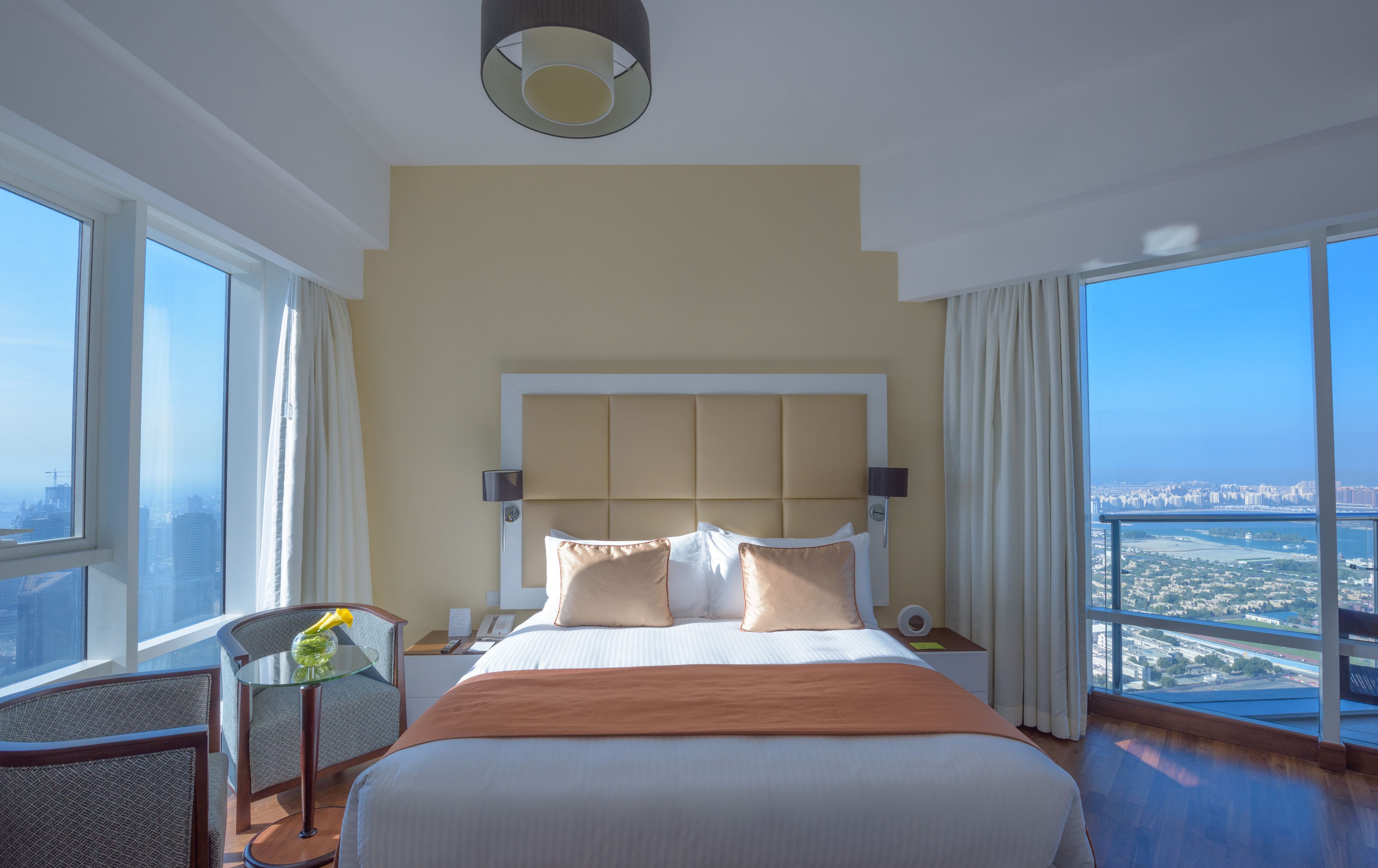 A hotel room with a large bed, a desk, a chair, and a view of the city.