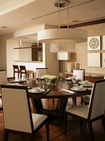 A dining area with a large wooden table set for six, surrounded by chairs.