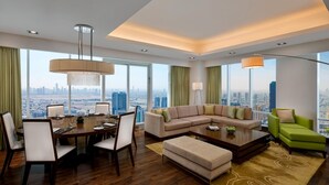 A modern living room with a dining area, large windows with city views, and a high ceiling. - La Suite Dubai Hotel & Apartments Operated by Minor Hotels (Dubai)