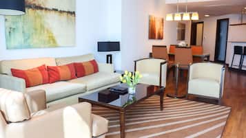 Uma sala de estar moderna com um sofá, poltronas, uma mesa de centro e uma área de jantar com cadeiras e uma mesa.