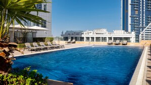 A swimming pool with lounge chairs and a building in the background. - La Suite Dubai Hotel & Apartments Operated by Minor Hotels (Dubai)