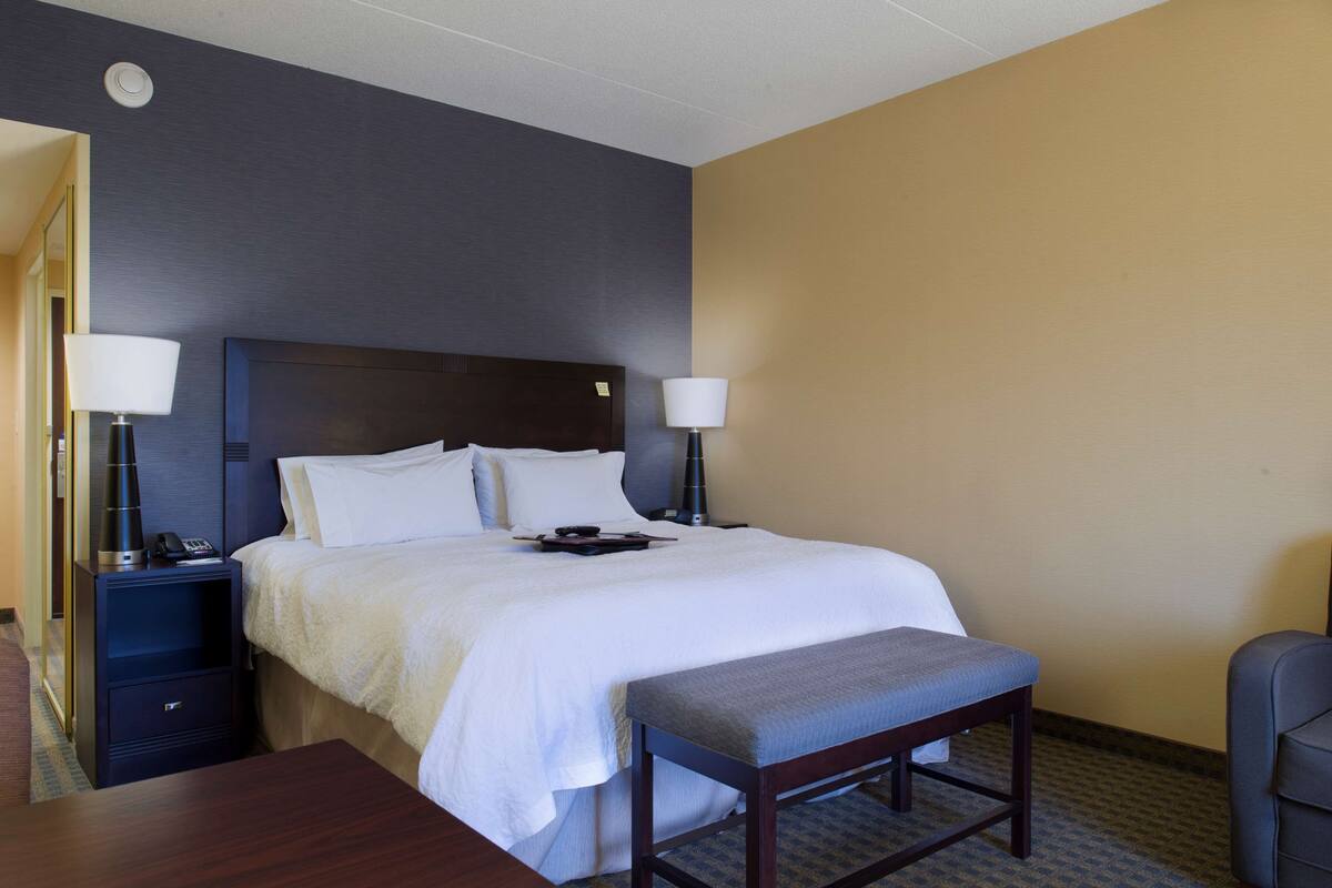 A hotel room with a large bed, two bedside tables, a desk, and a chair.