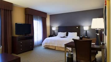 A hotel room with a bed, a TV, a desk, and a chair.