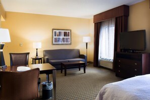 A hotel room with a sofa, a TV, a desk, and a chair. - Hampton Inn & Suites Vineland (Vineland)