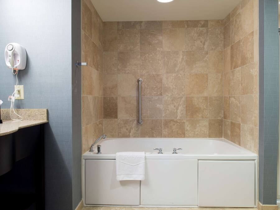 A modern bathroom with a bathtub, a towel rack, and a hand dryer on the wall.