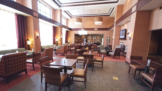 A spacious hotel lobby with multiple seating areas, including a large dining table and several chairs. - Hampton Inn & Suites Vineland (Vineland)