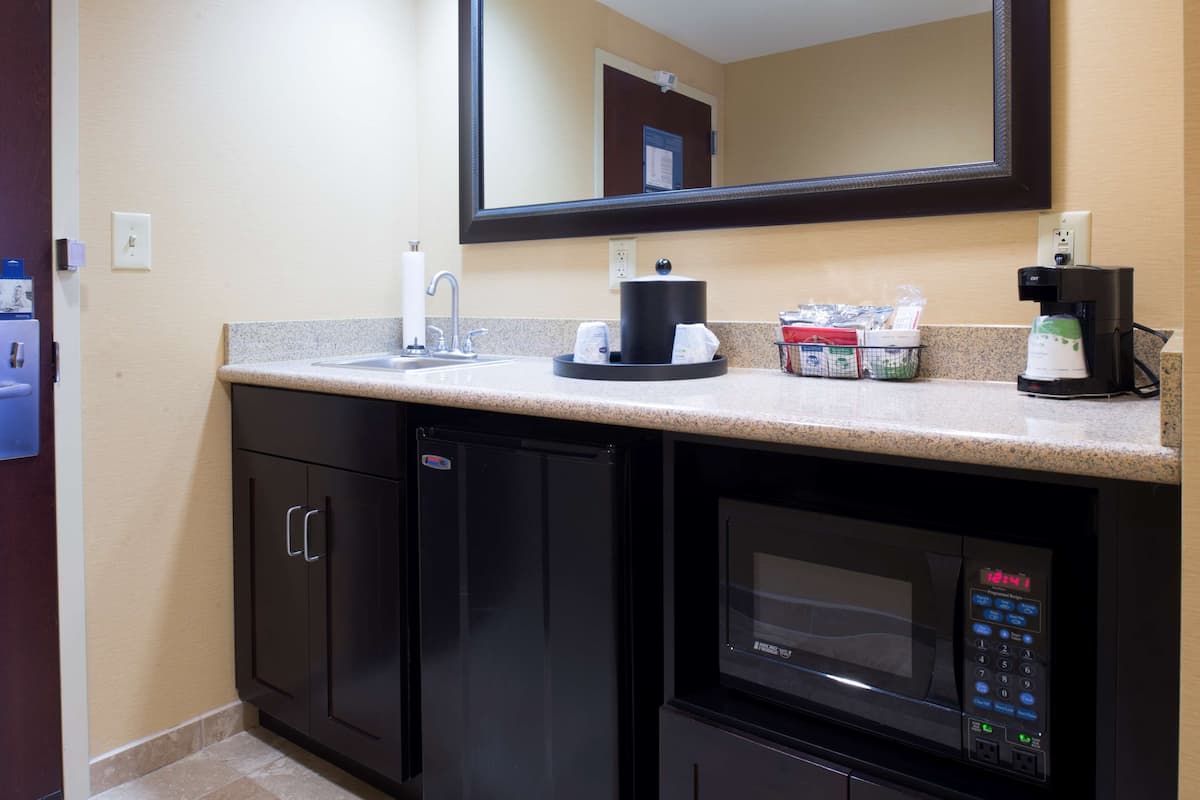 A modern kitchen with a microwave, coffee maker, and a sink.