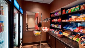 Un espace de libre-service où l'on peut acheter des collations et des boissons, avec des boissons réfrigérées, une variété de collations emballées et un comptoir de caisse.