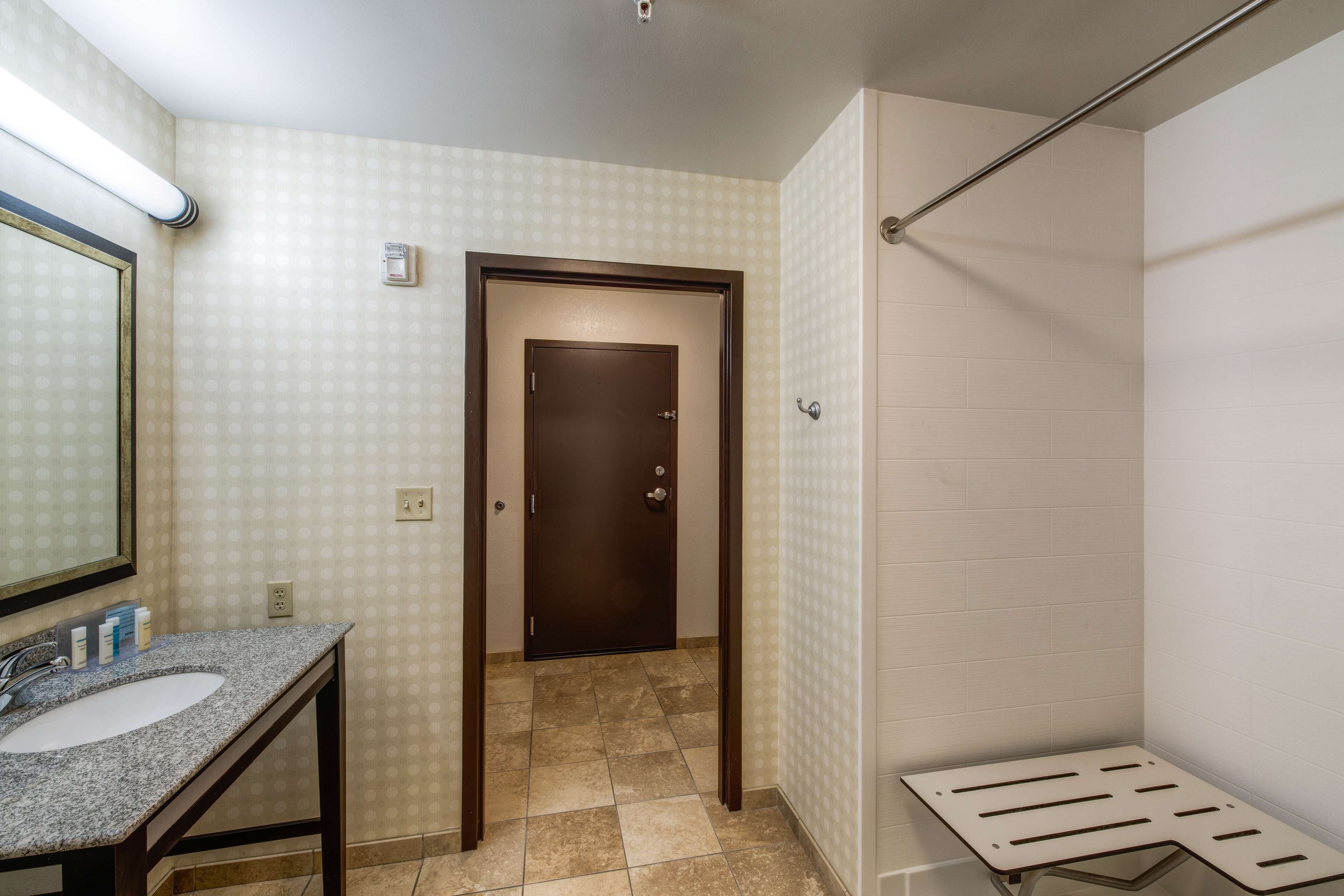 A bathroom with a sink, mirror, and shower area.