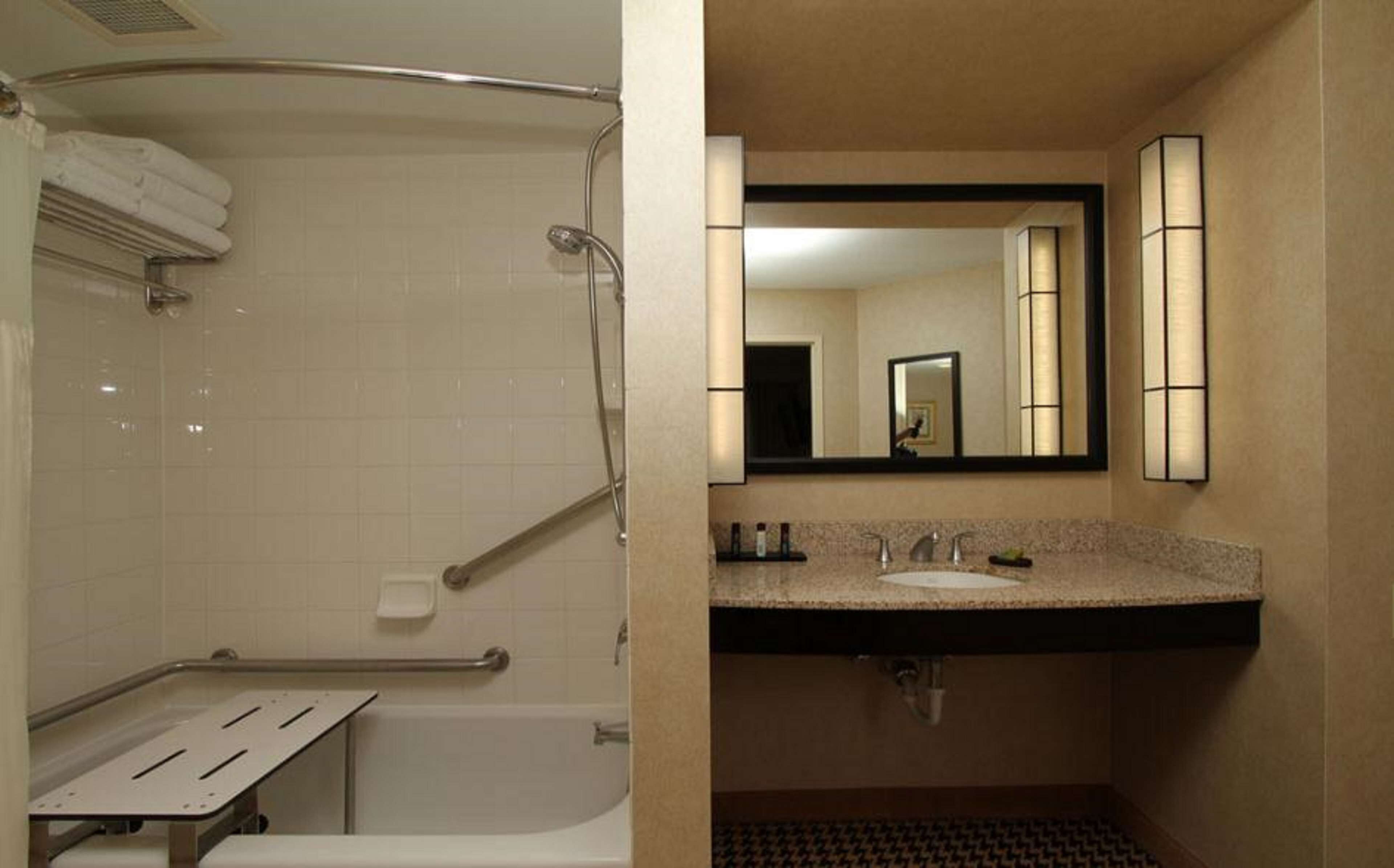 A bathroom with a bathtub, a shower, a sink with a vanity, and a mirror.