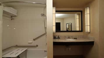 A bathroom with a bathtub, a shower, a sink with a vanity, and a mirror.