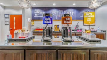 A breakfast bar with two coffee dispensers labeled "DARK ROAST" and "LIGHT ROAST," and a sign that reads "HAPPY BREAKFAST STARTS HERE."