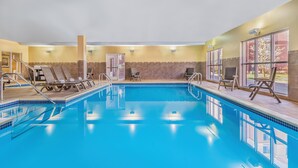Une piscine intérieure à l’eau d’un bleu cristallin, dotée de chaises longues et d’une terrasse carrelée.