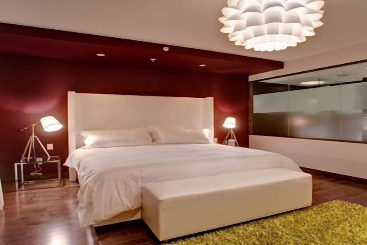 A modern bedroom with a large bed, bedside lamps, a window, and a unique ceiling light fixture.