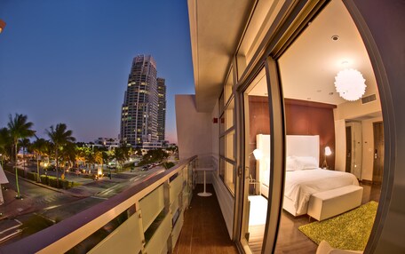 A balcony with a city view, a bedroom with a bed and a nightstand, and a large window.