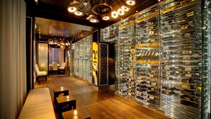 A wine cellar with rows of wine bottles, wooden benches, and a chandelier.