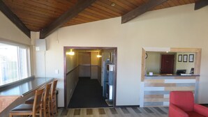 A modern kitchen with a wooden ceiling, a bar area with stools, and a red chair. - Americas Best Value Inn Story City (Story City)
