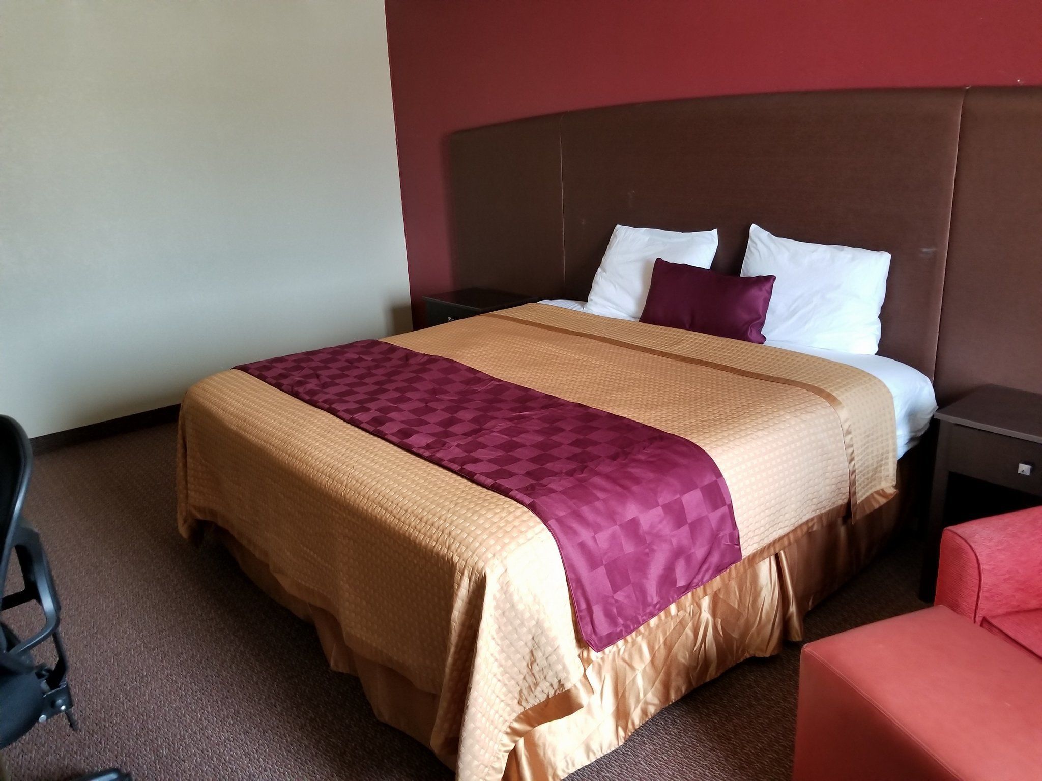Une chambre d’hôtel avec un grand lit, une table de chevet, une chaise rouge et un bureau.