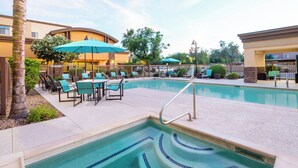 A pool area with lounge chairs and umbrellas, surrounded by a fence and trees. - Residence Inn Phoenix NW/Surprise (Surprise)