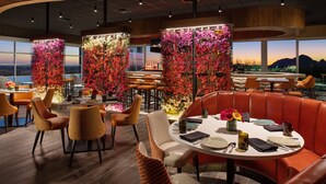 A restaurant with high tables and booths, floral wall decorations, and a view of the mountains.