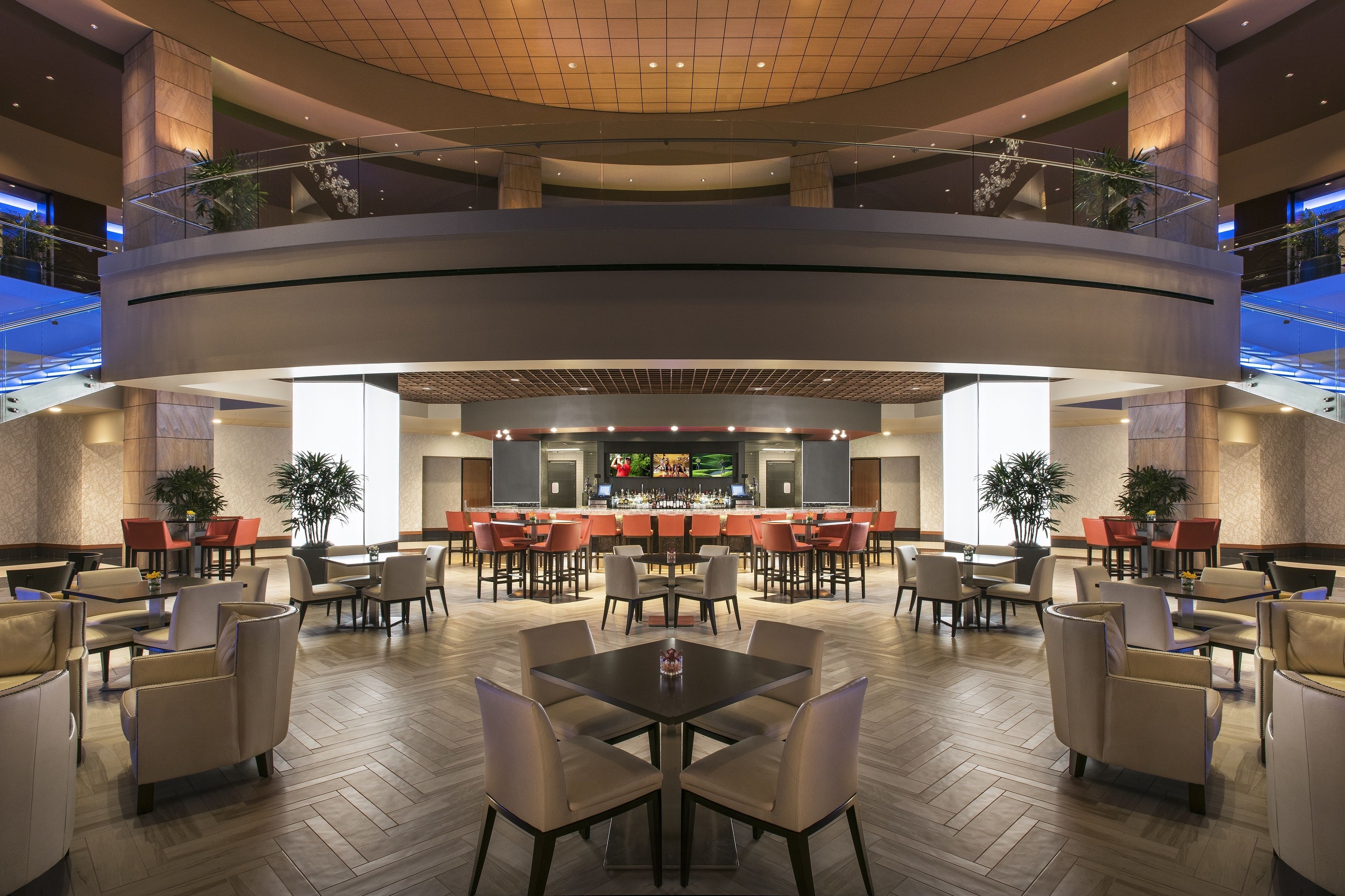 A spacious lobby with multiple seating areas, a central bar, and a high ceiling with a grid pattern.