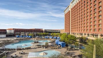 A hotel with multiple swimming pools, outdoor seating areas, and a large building with a red facade.
